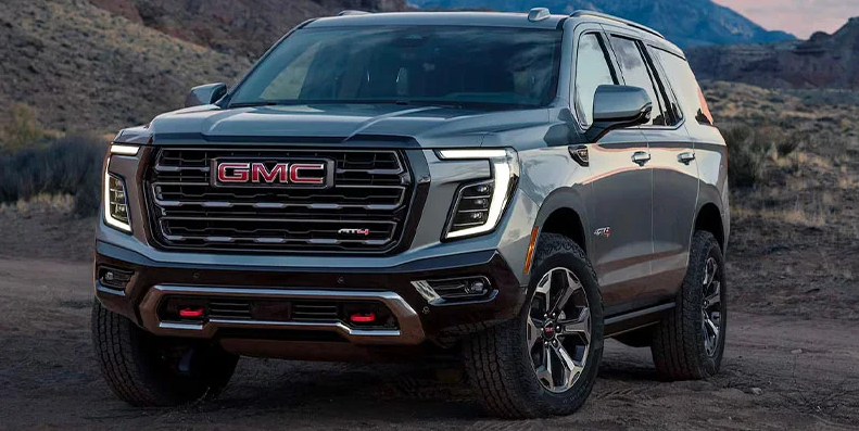 A silver GMC Yukon parked on a dirt road.